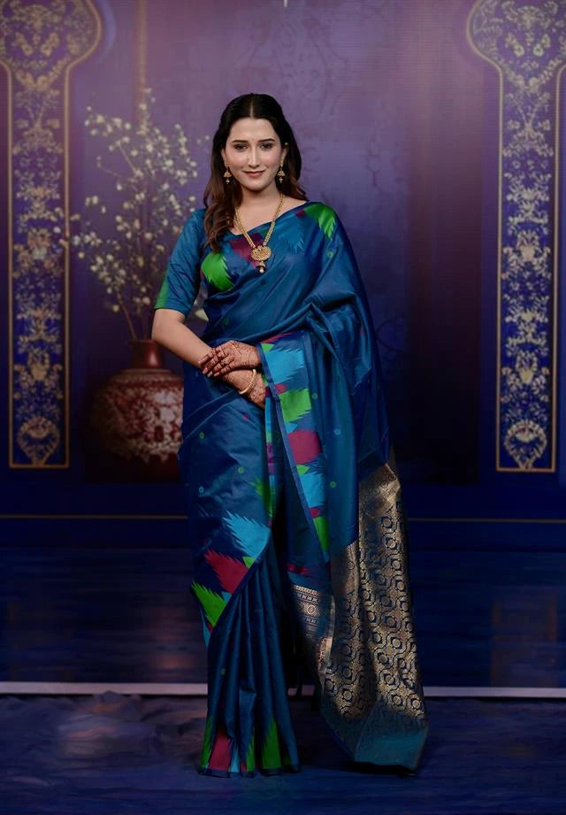 Woman wearing a blue saree with colorful patterns against a dark background