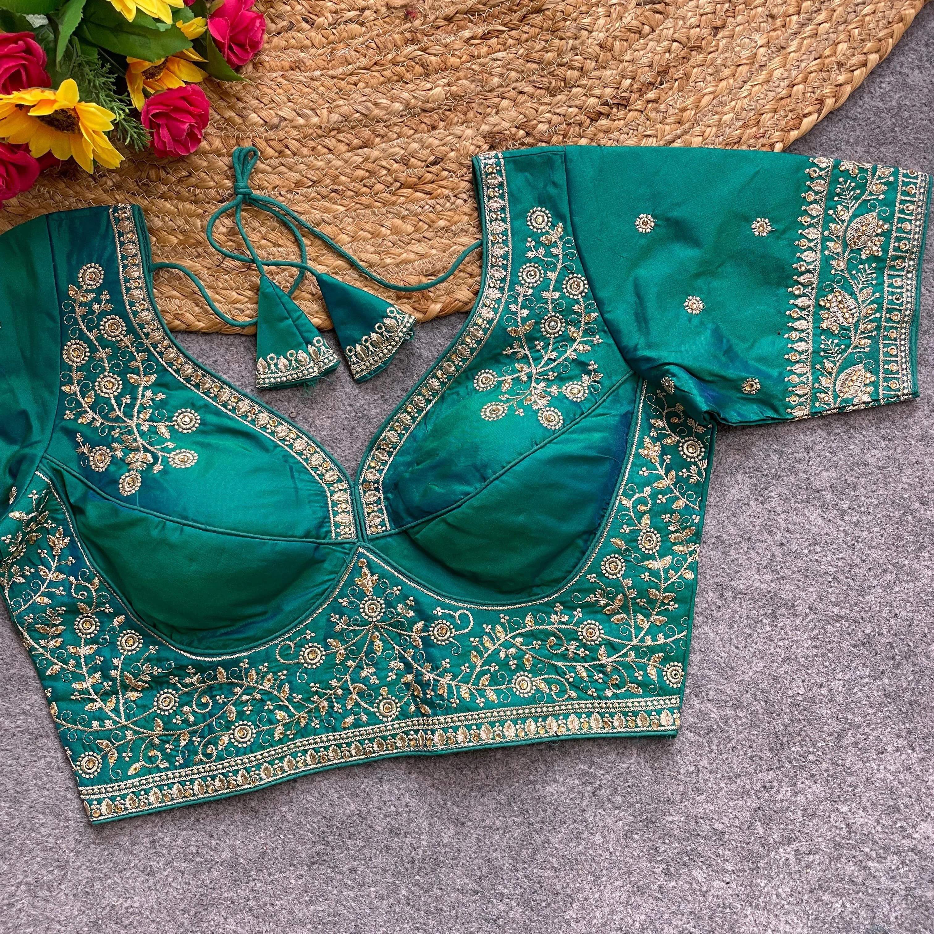 Green embroidered blouse on a textured surface with flowers in the background