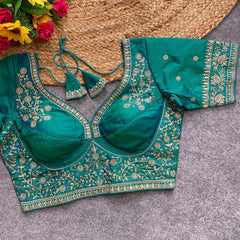 Green embroidered blouse on a textured surface with flowers in the background