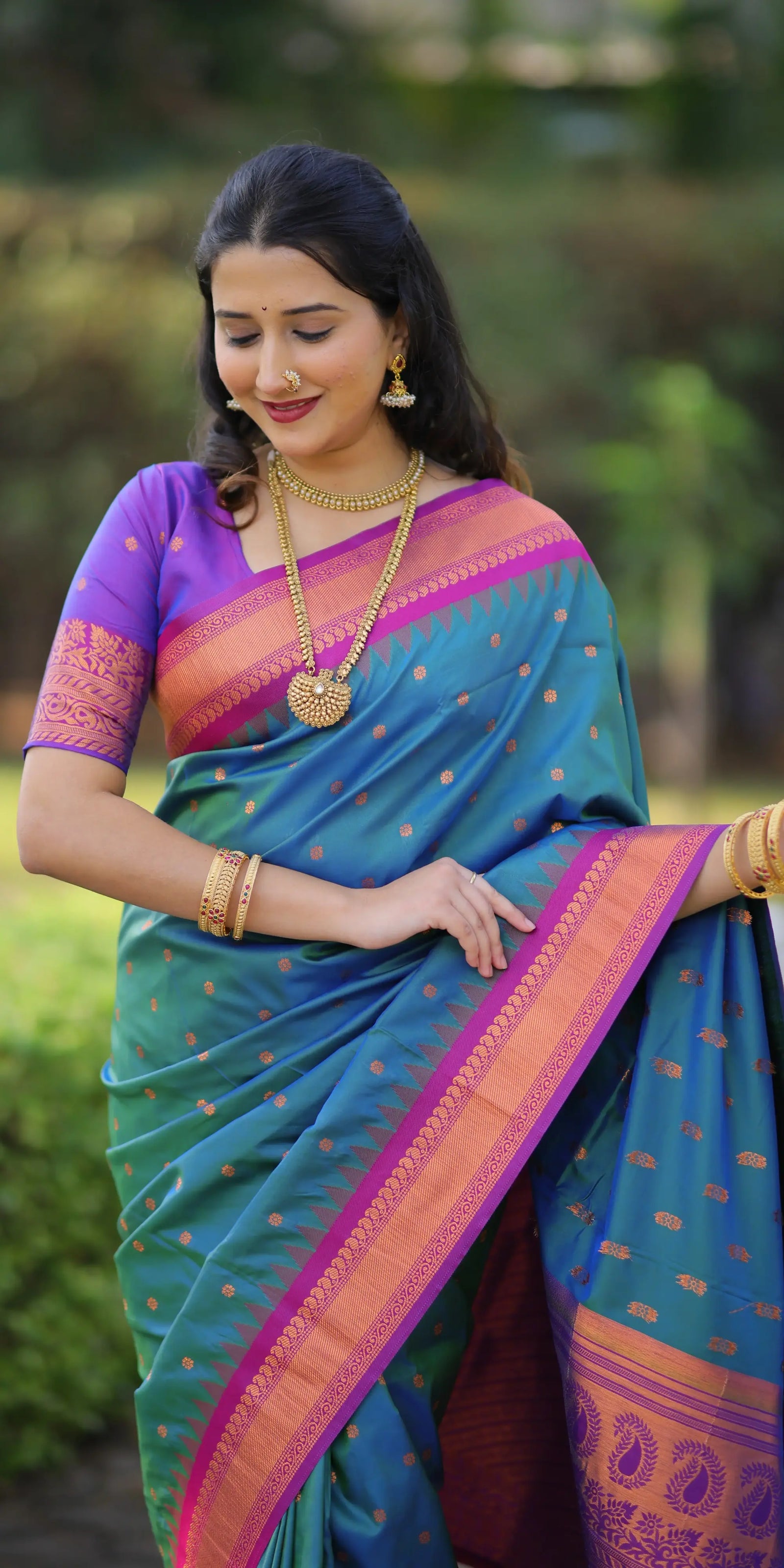 Woman wearing a blue saree with pink and purple border outdoors