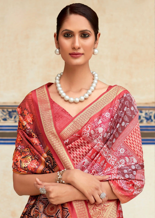 Woman wearing a red saree with floral patterns and a pearl necklace against a decorative wall.