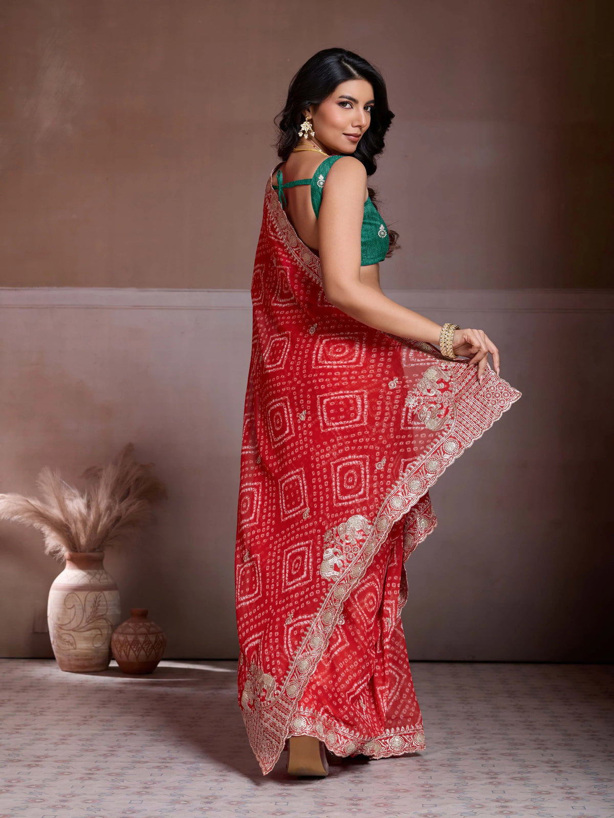 Woman wearing a red saree with white patterns against a neutral background
