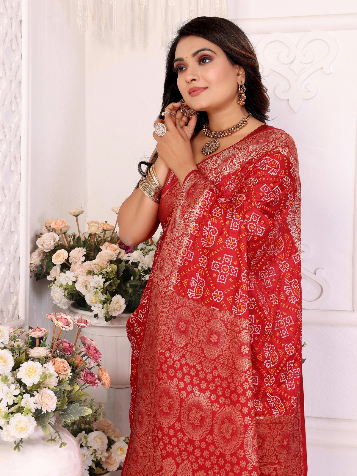 Woman wearing a red saree with floral decorations and flowers in the background