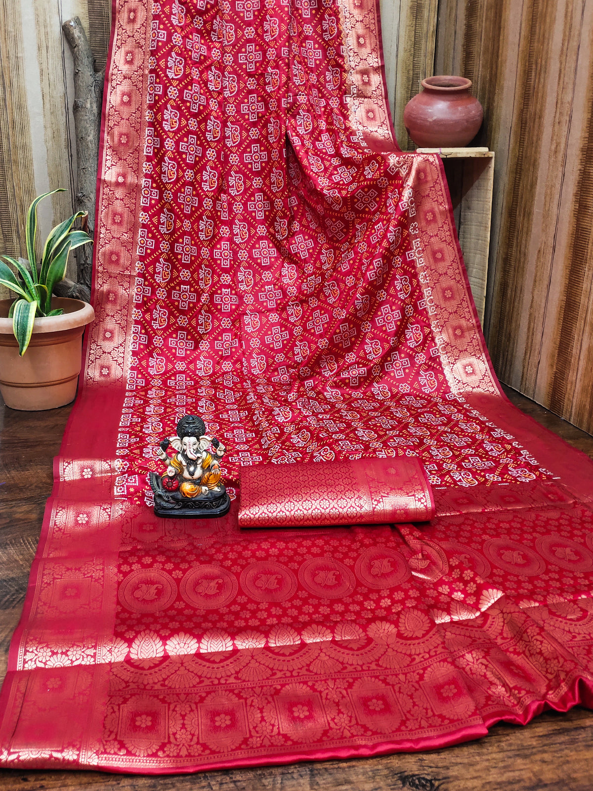 Red patterned fabric with a small statue on a wooden surface