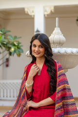 Woman in a red outfit with a colorful shawl sitting outdoors.