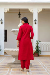 Person wearing a red outfit standing in a decorative indoor setting.