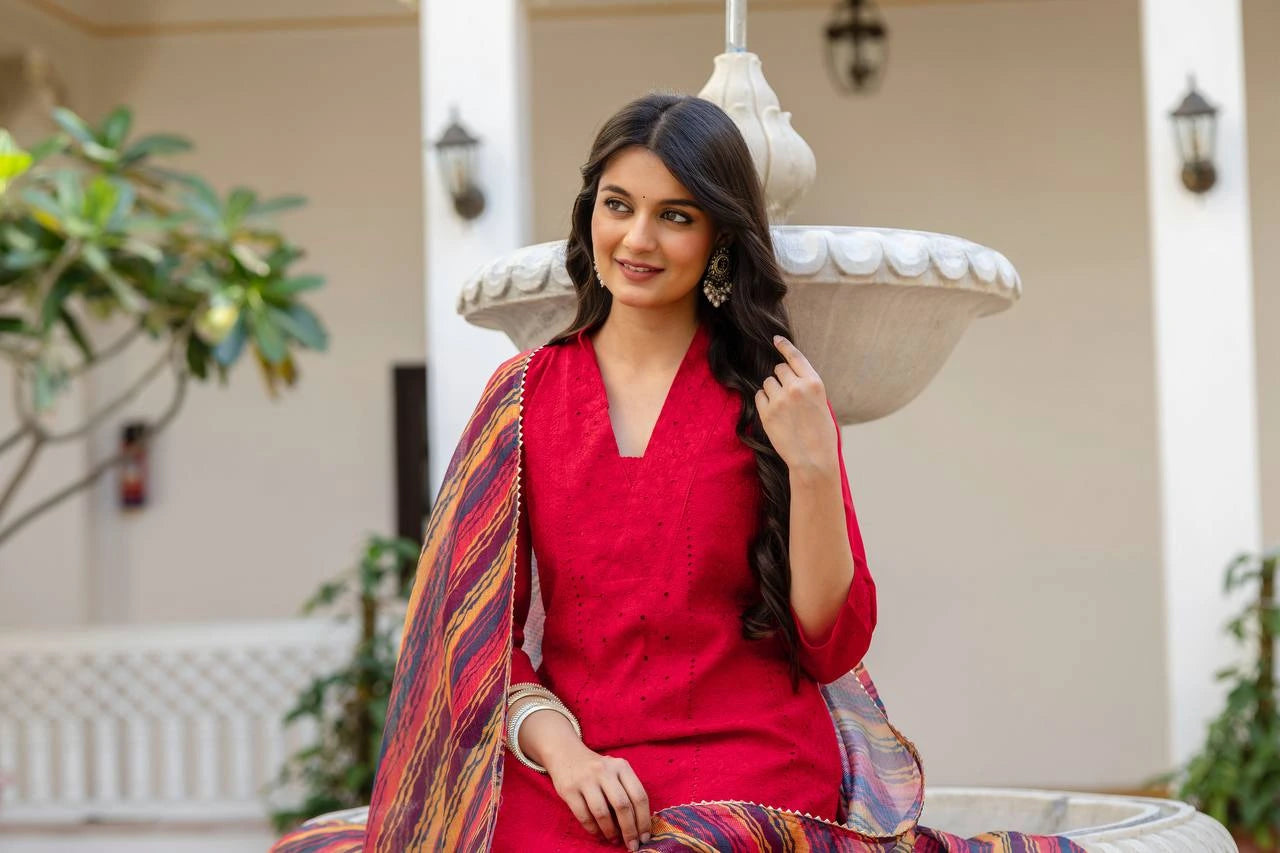 Woman in a red outfit with a colorful shawl sitting outdoors.