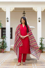 Woman in a red outfit with a colorful shawl standing in an indoor setting.