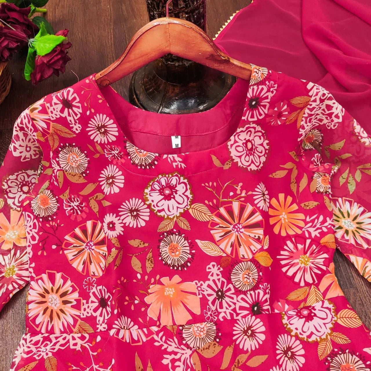 Pink floral-patterned garment on a wooden hanger