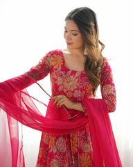 Woman wearing a vibrant pink traditional outfit with floral patterns on a white background