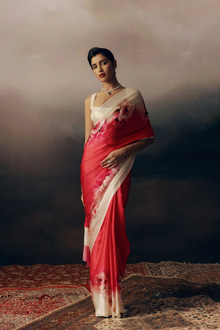 Woman in a red and white saree with floral patterns on a textured floor.