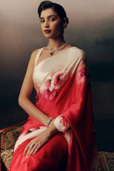 Woman wearing a red saree with floral patterns, sitting on a textured surface.