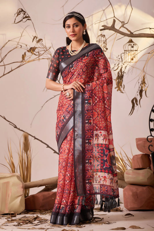 Woman wearing a red patterned saree with a black blouse in an indoor setting.