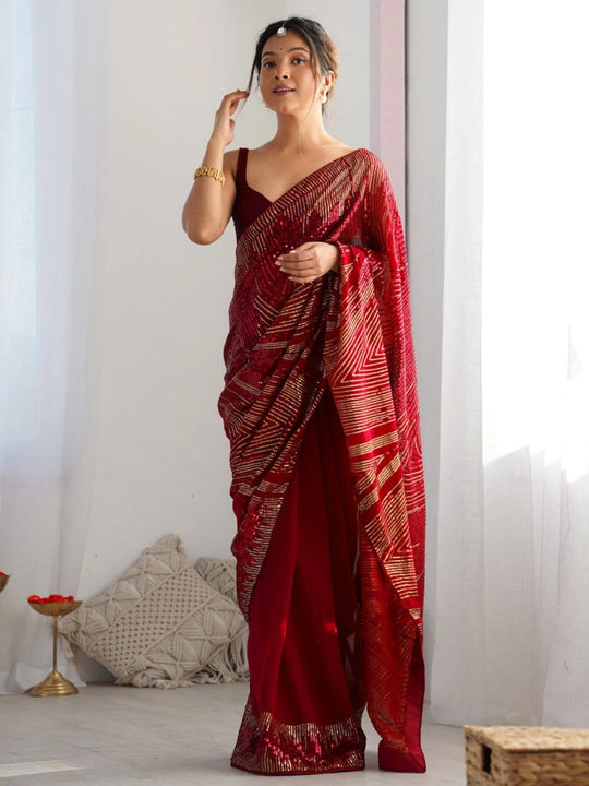 Woman wearing a red saree with white patterns in a minimal indoor setting