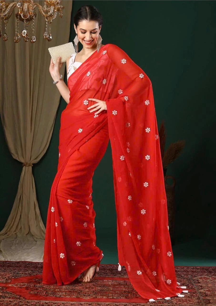 Woman wearing a red saree with white patterns against a dark background