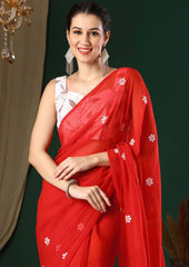 Woman wearing a red saree with white patterns against a dark background