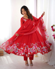 Woman wearing a red traditional outfit with floral patterns in a bright room.
