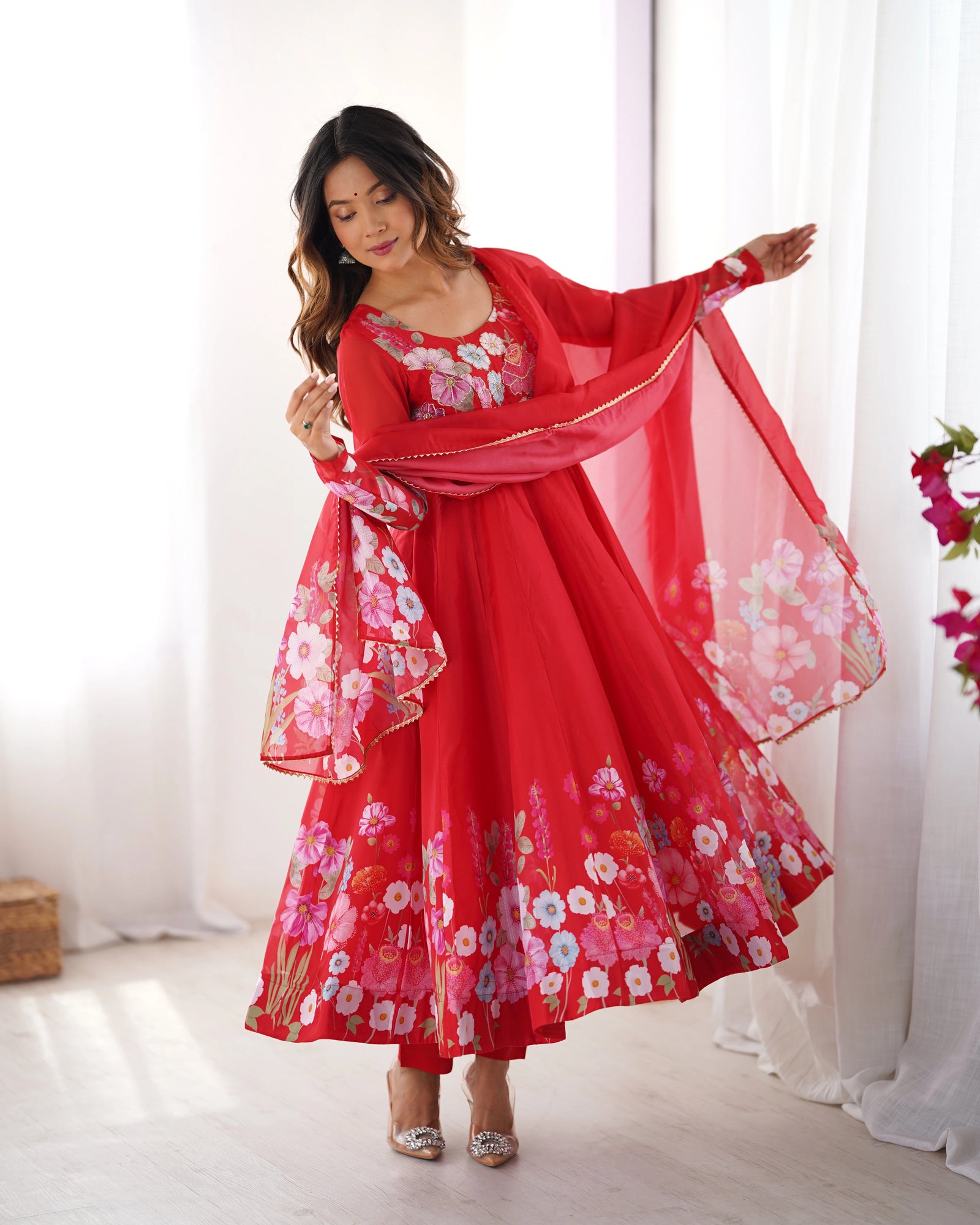 Woman wearing a red floral dress with a matching scarf in a bright room.