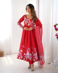 Woman wearing a red floral dress with a pink dupatta against a white curtain background
