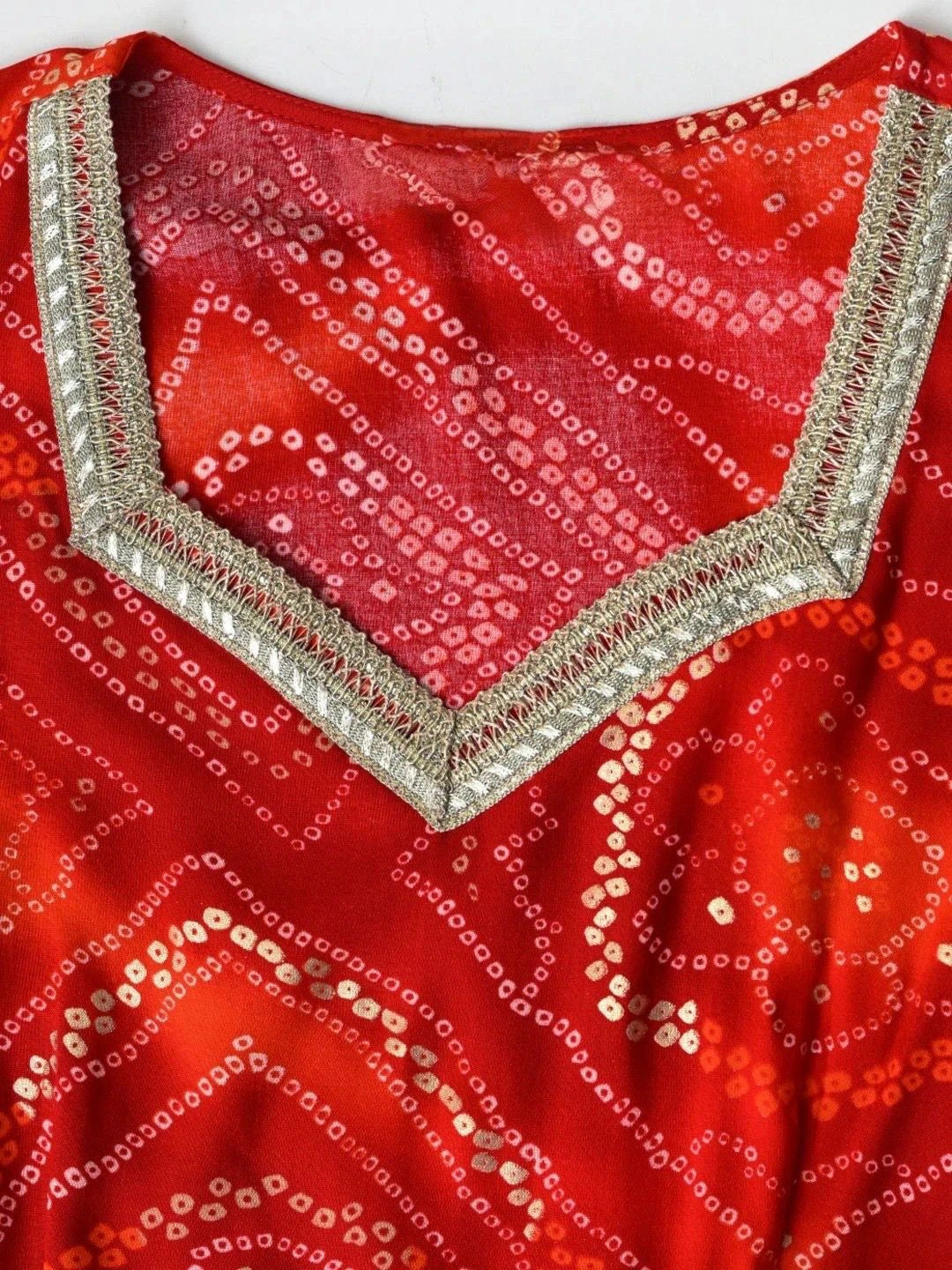 Red garment with intricate white patterns and embellishments on a plain background