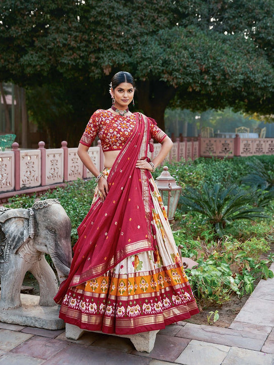 Woman in traditional Indian saree standing outdoors with greenery and stone elephant in the background