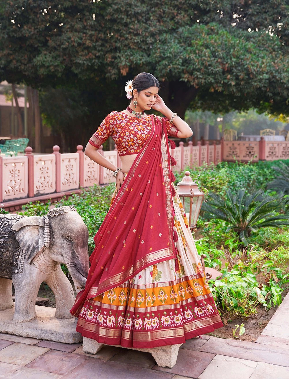 Woman in a red saree with floral decorations in an outdoor setting