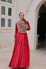 Woman in traditional red and patterned outfit standing in front of a building entrance.