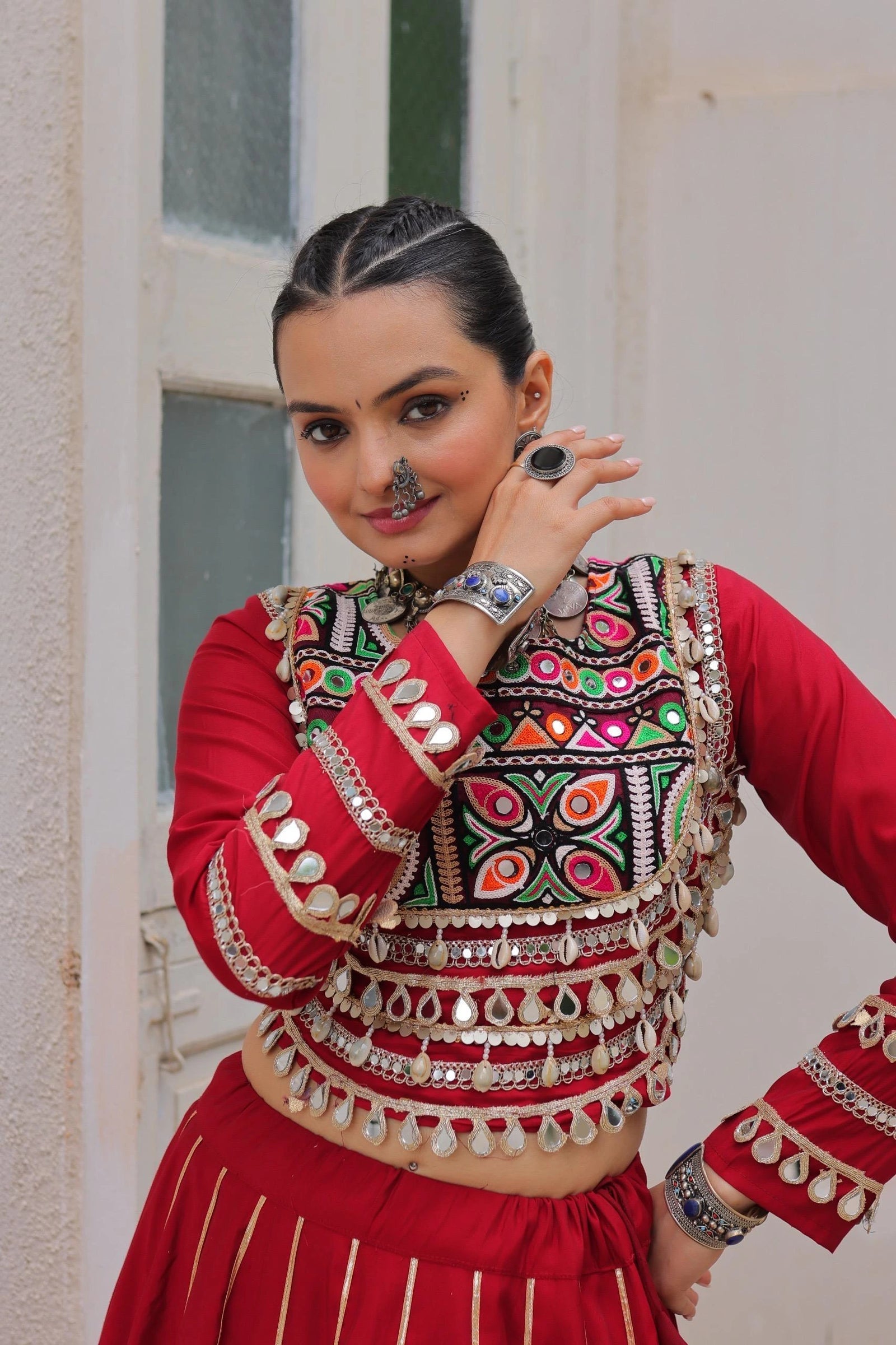 Woman in traditional red and multicolored outfit with intricate designs.