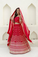 Woman in a red and white traditional outfit with a matching dupatta against a white background