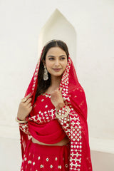 Woman in a red traditional outfit with gold details on a white background