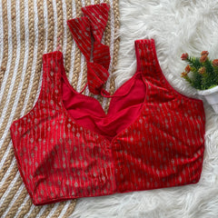 Red patterned top on a textured surface with a small plant.