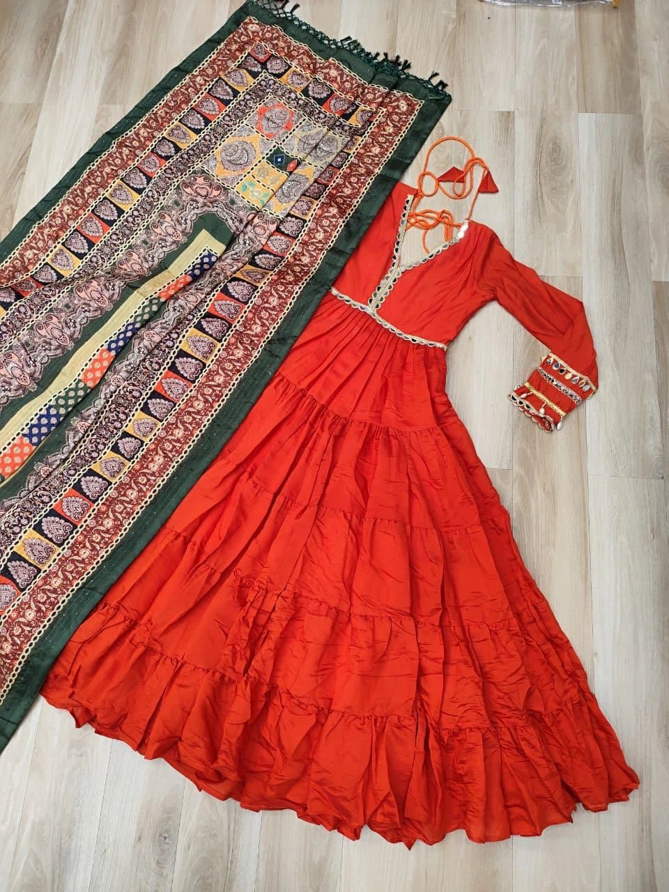 Red traditional dress with long sleeves and intricate patterns on a wooden floor.
