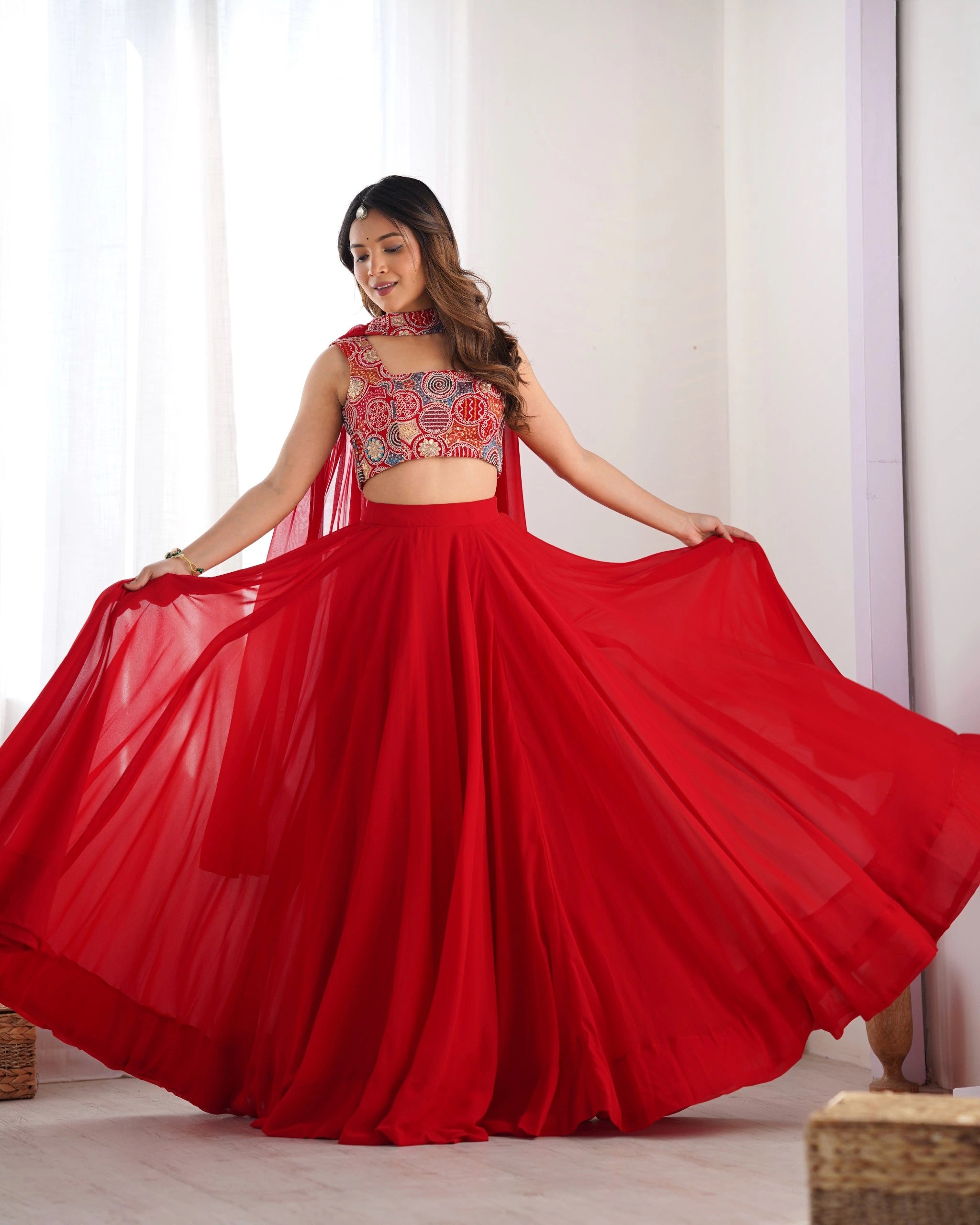 Woman wearing a red traditional outfit with a patterned top and flowing skirt.