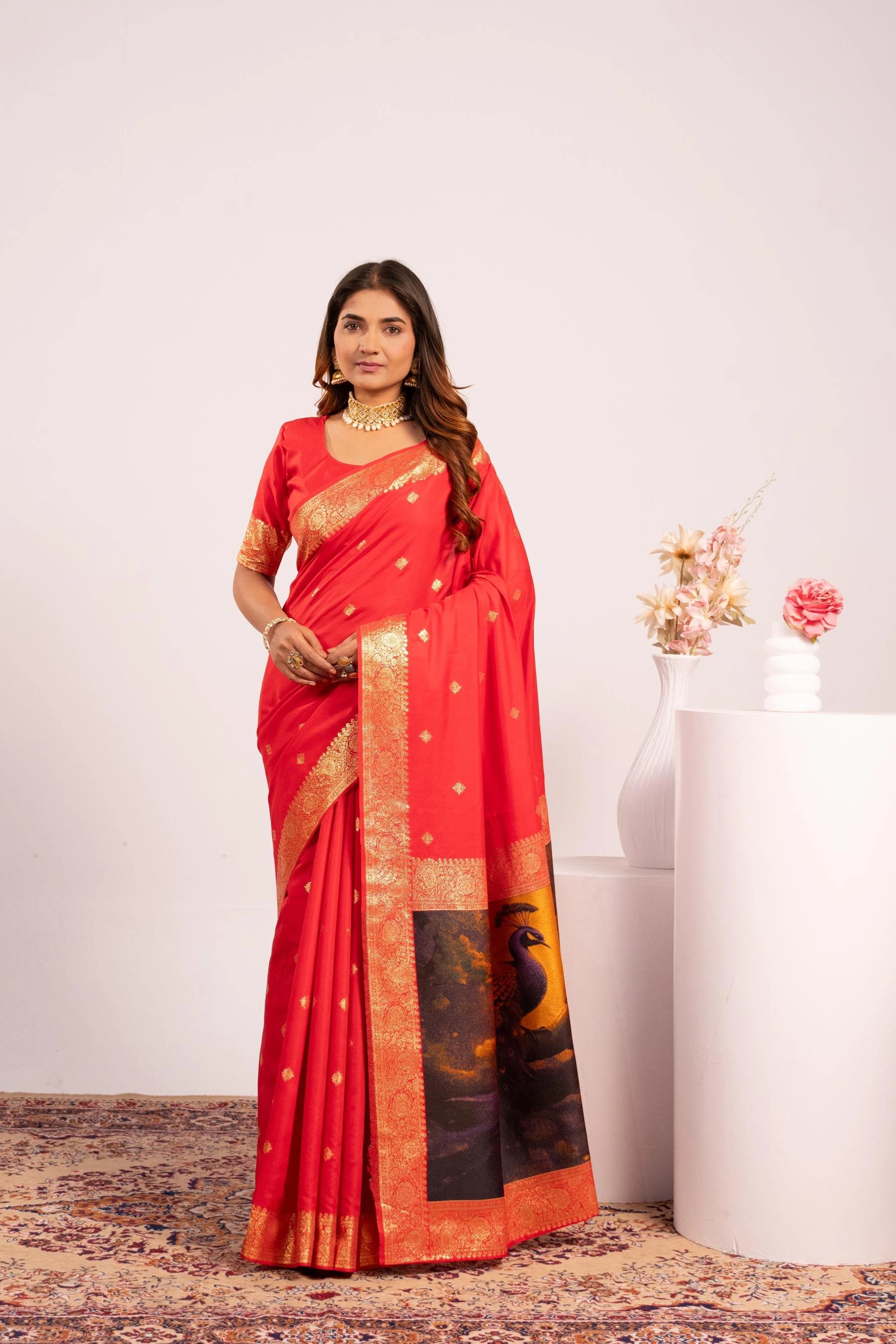 Woman wearing a red saree with gold and black patterns on a white background