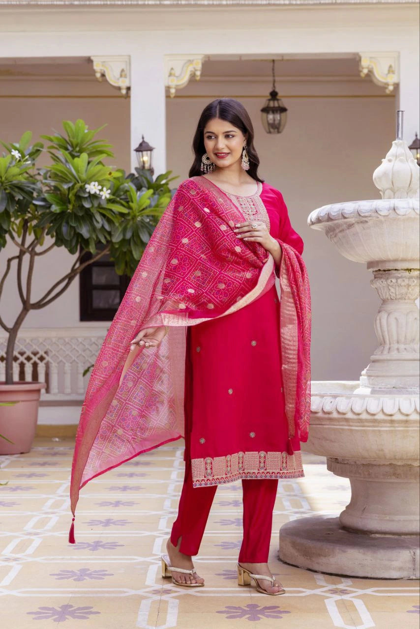 Woman in a red traditional outfit with a pink dupatta standing in an outdoor setting.