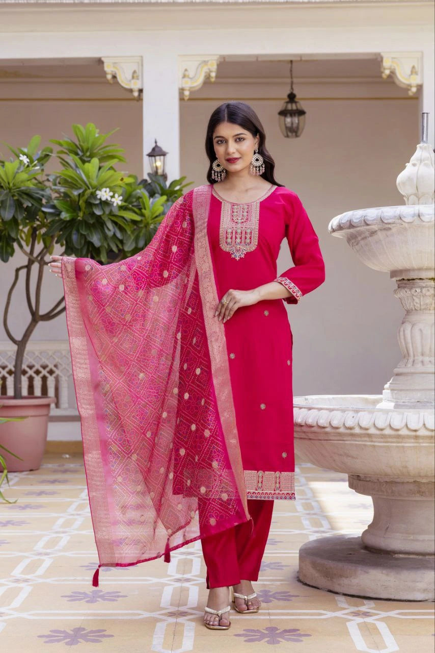 Woman in a pink traditional outfit standing in an outdoor setting with decorative elements.