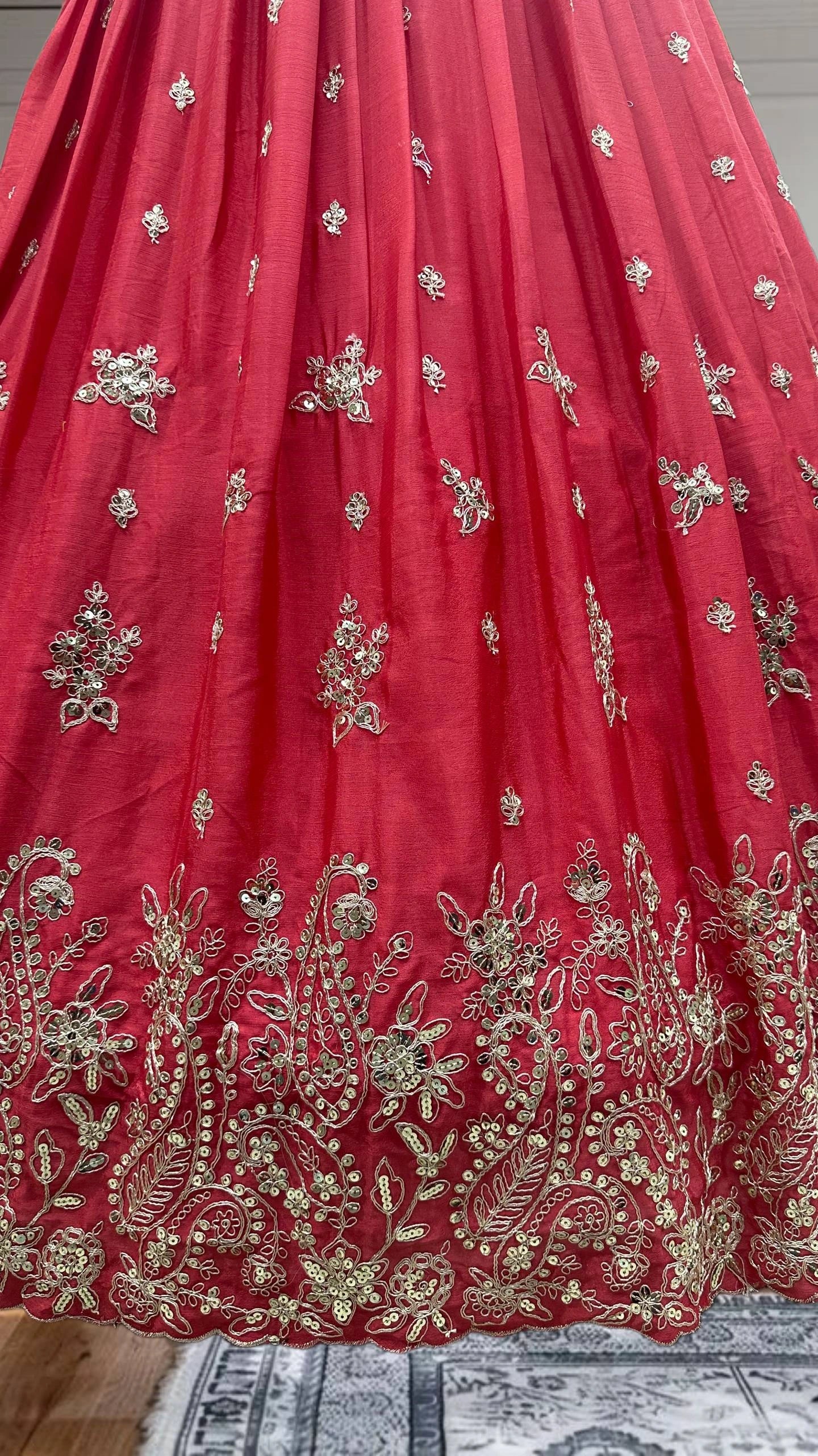 Red fabric with gold embroidery on a wooden surface