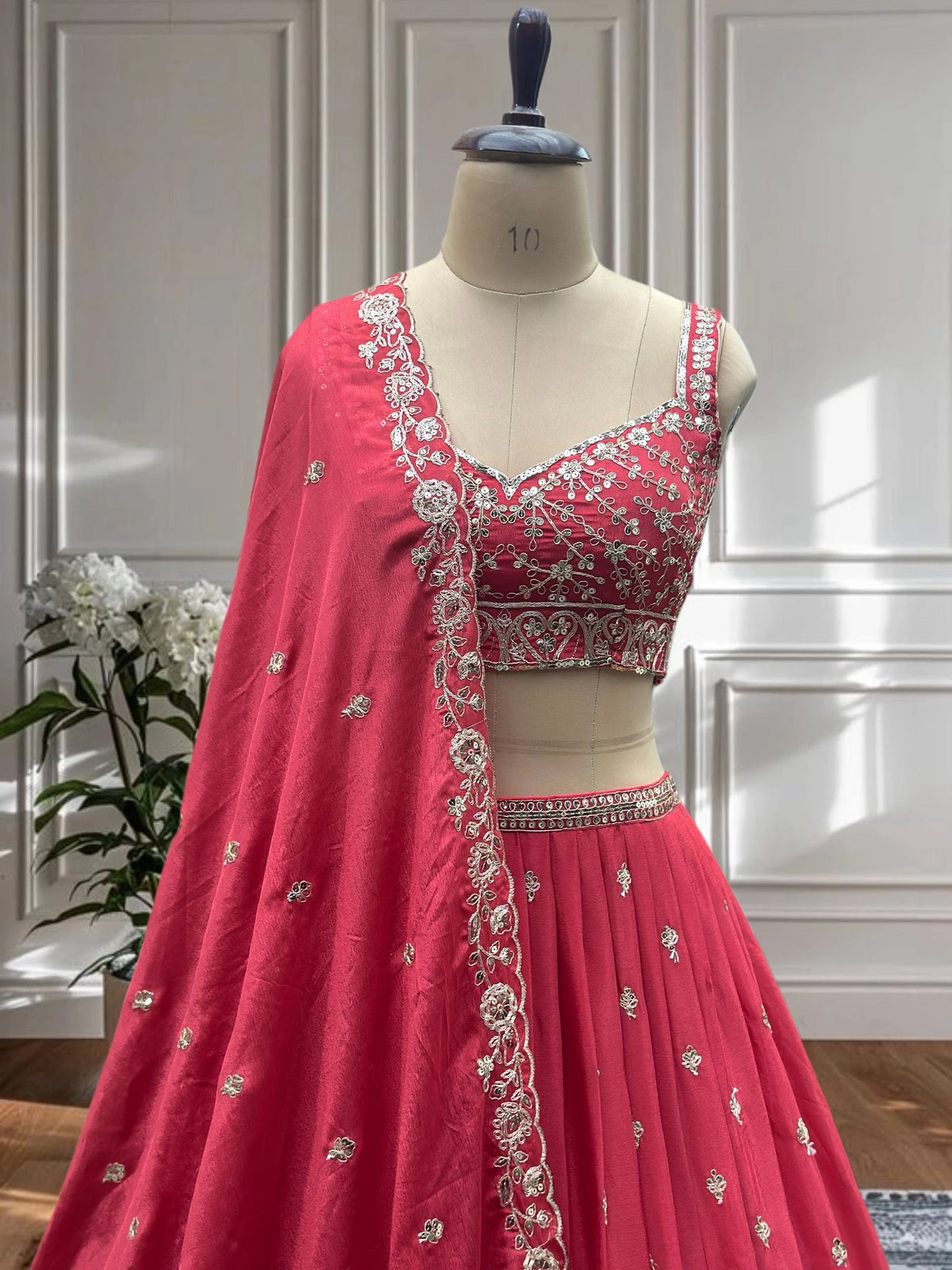 Red embroidered lehenga on a mannequin against a neutral background