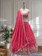 Pink embroidered lehenga on a mannequin against a white paneled wall.