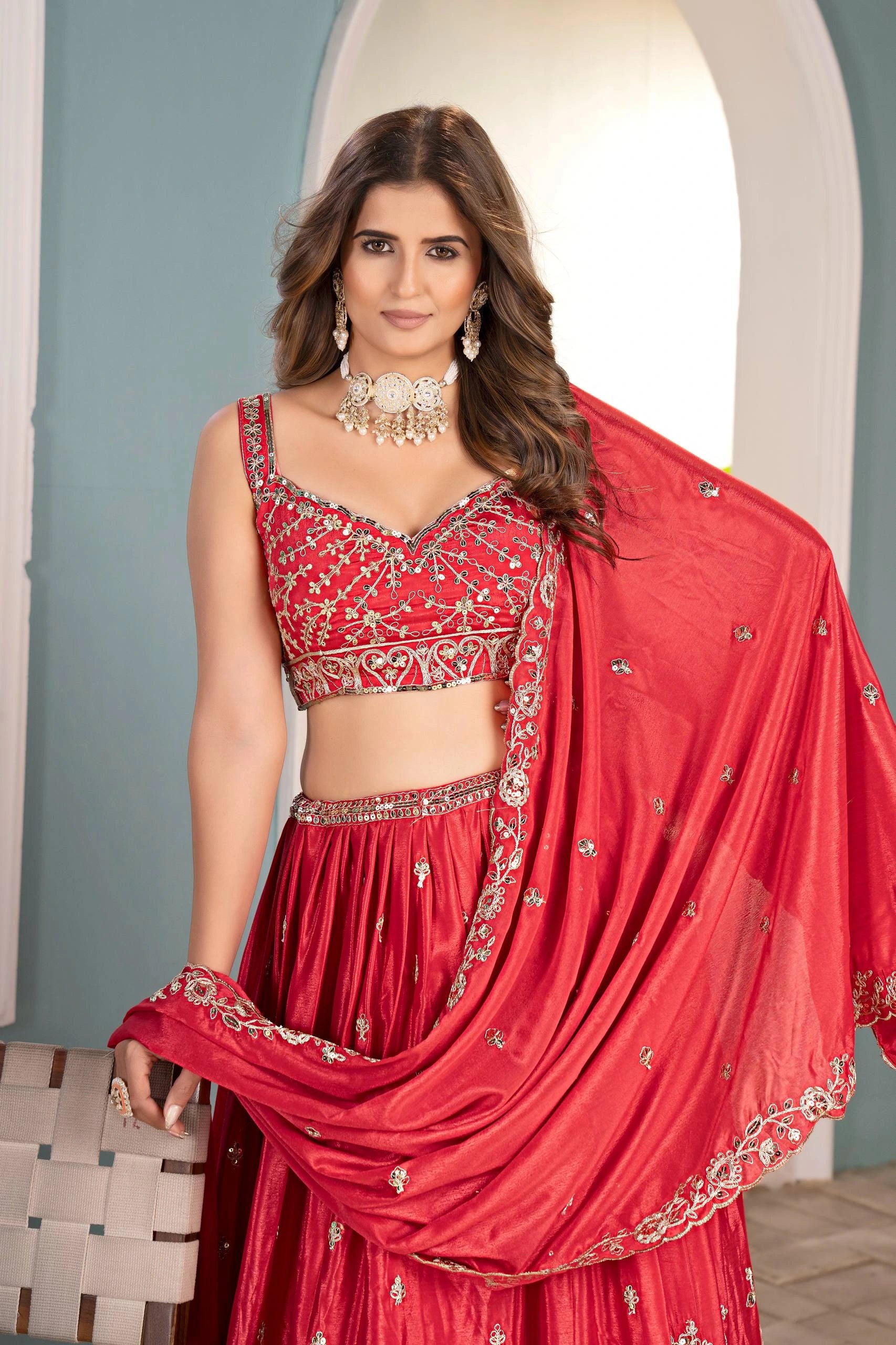 Woman wearing a red traditional outfit with intricate designs indoors.