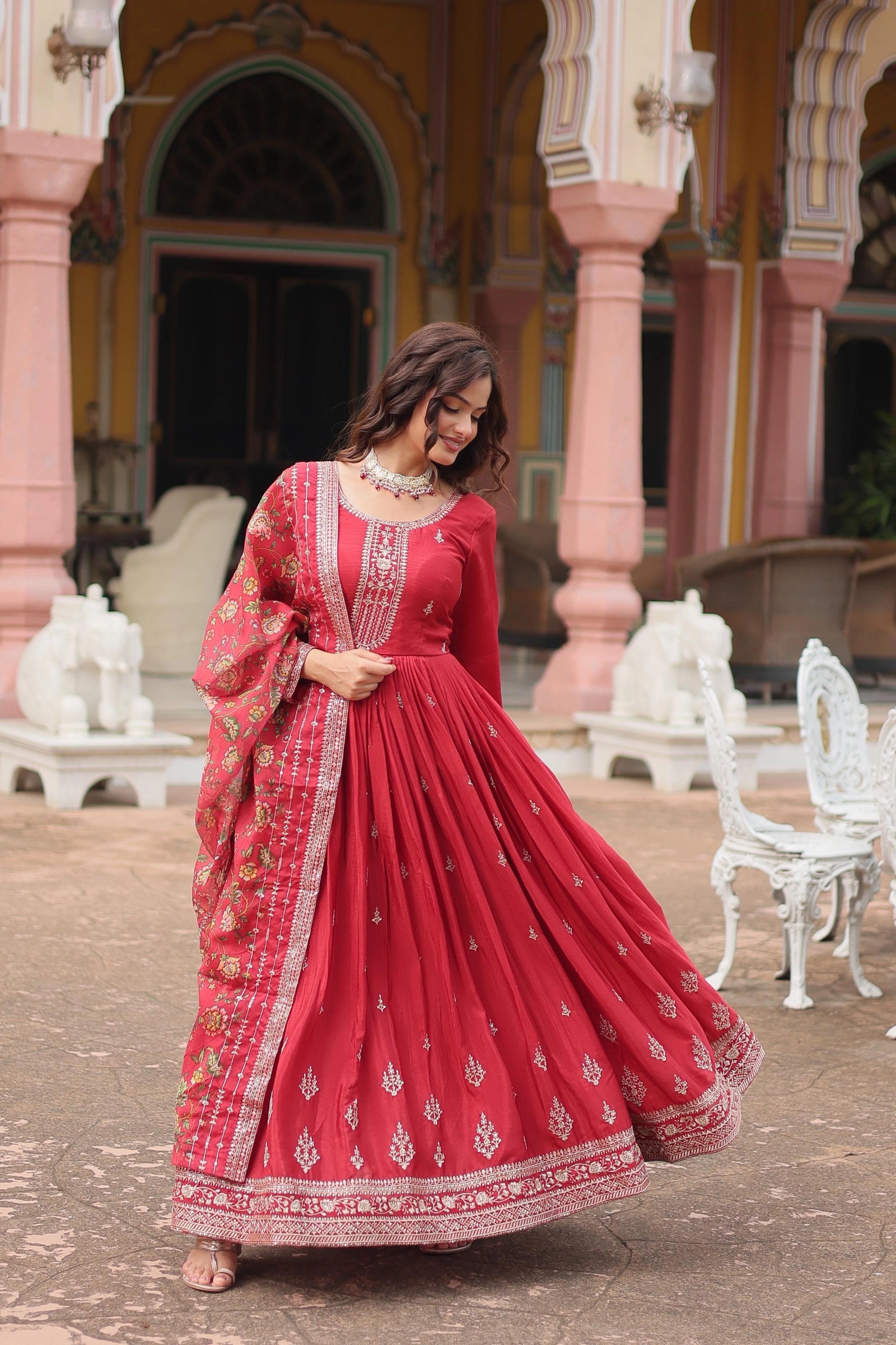 Woman in a red traditional outfit standing in front of an ornate building.