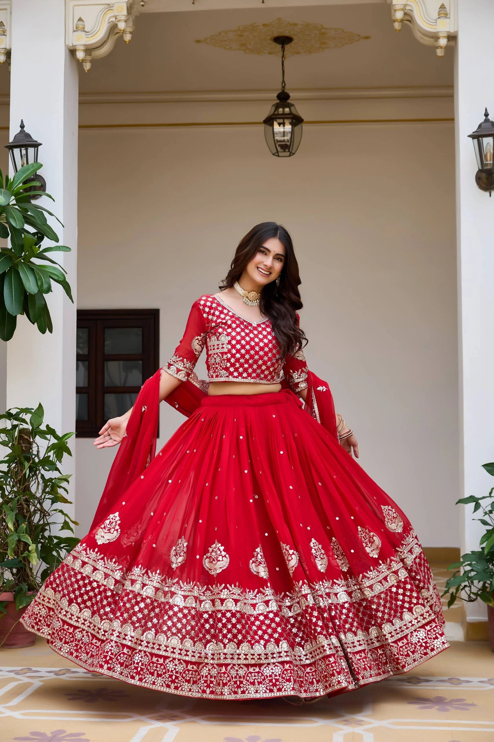 Woman in a red and white traditional outfit standing in an elegant indoor setting.