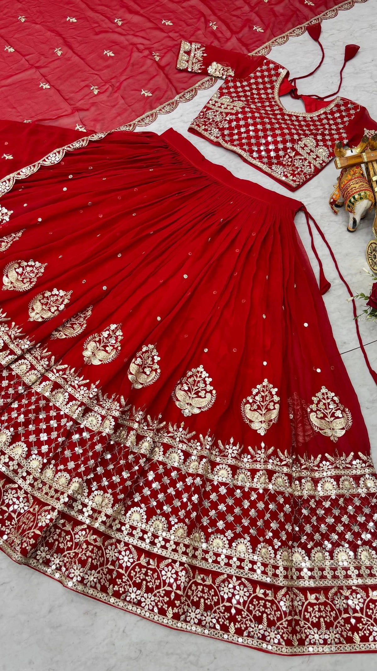 Red embroidered traditional outfit with gold details on a light gray background