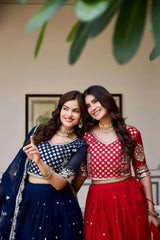 Two women in traditional outfits standing close together indoors.