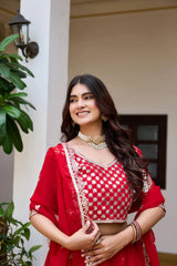 Woman in a red and white traditional outfit standing outdoors.