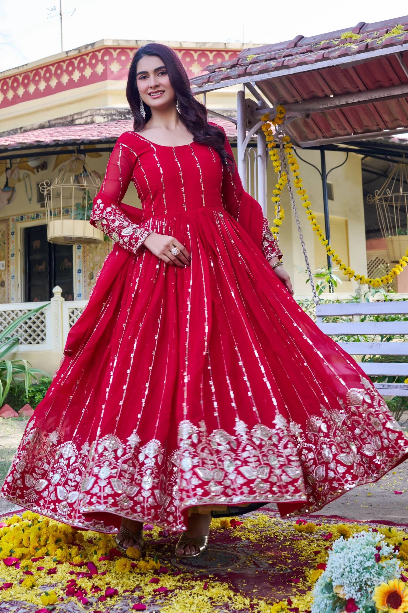 Woman in a red traditional outfit with white embroidery standing in front of a decorated building.