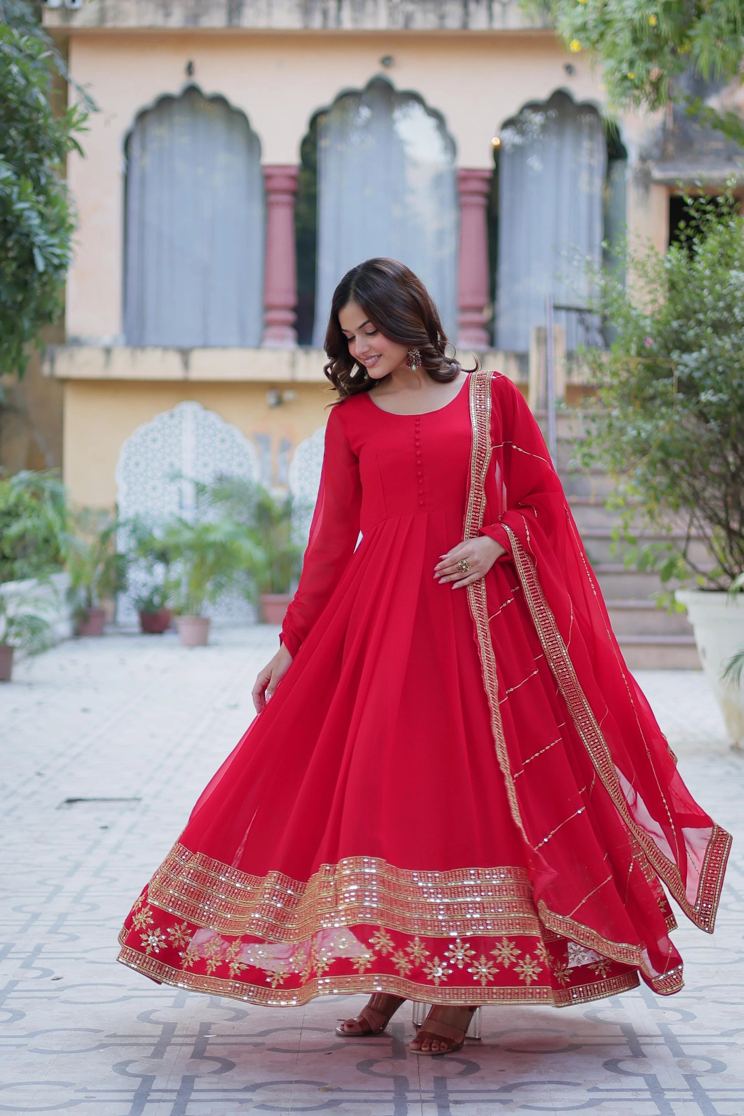Woman in a red traditional outfit standing outdoors with a building in the background