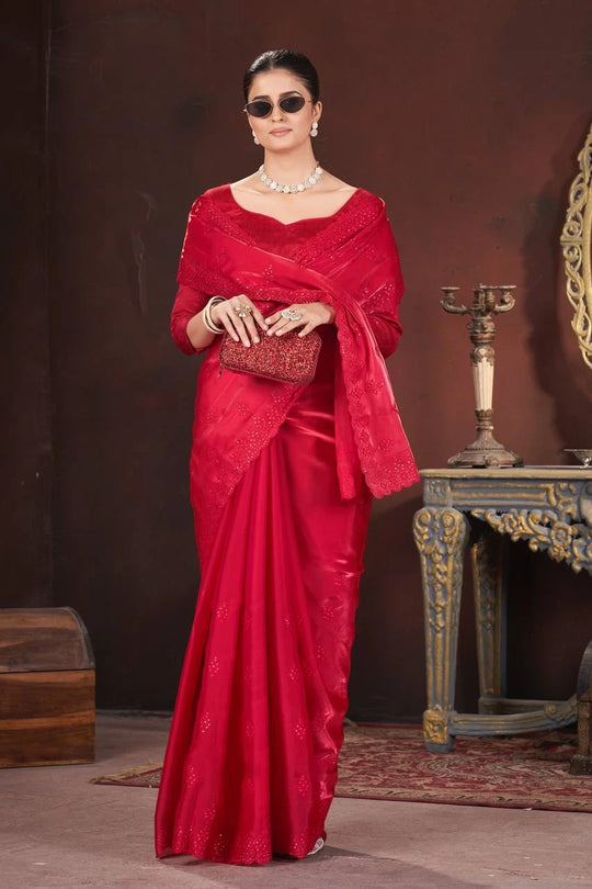 Woman in a red saree with a matching shawl against a dark background