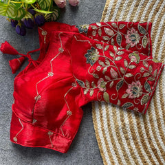 Red embroidered blouse on a textured surface with flowers in the background