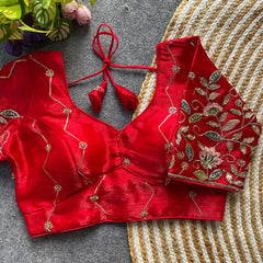 Red embroidered blouse on a textured surface with flowers in the background